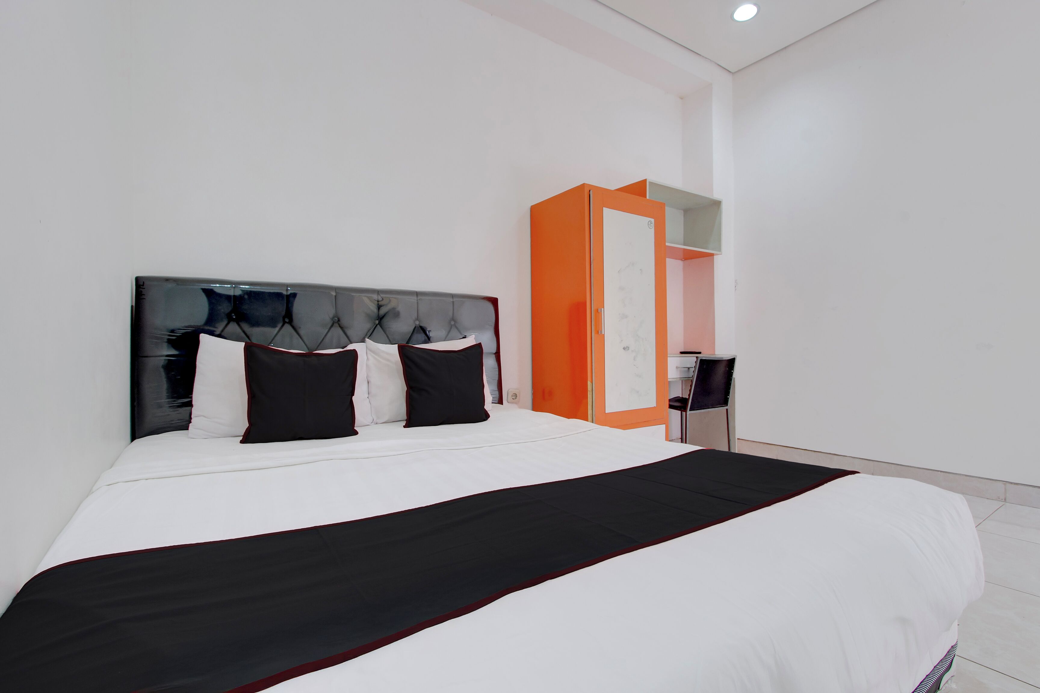 A modern hotel room with a large bed, a wardrobe, and a desk.