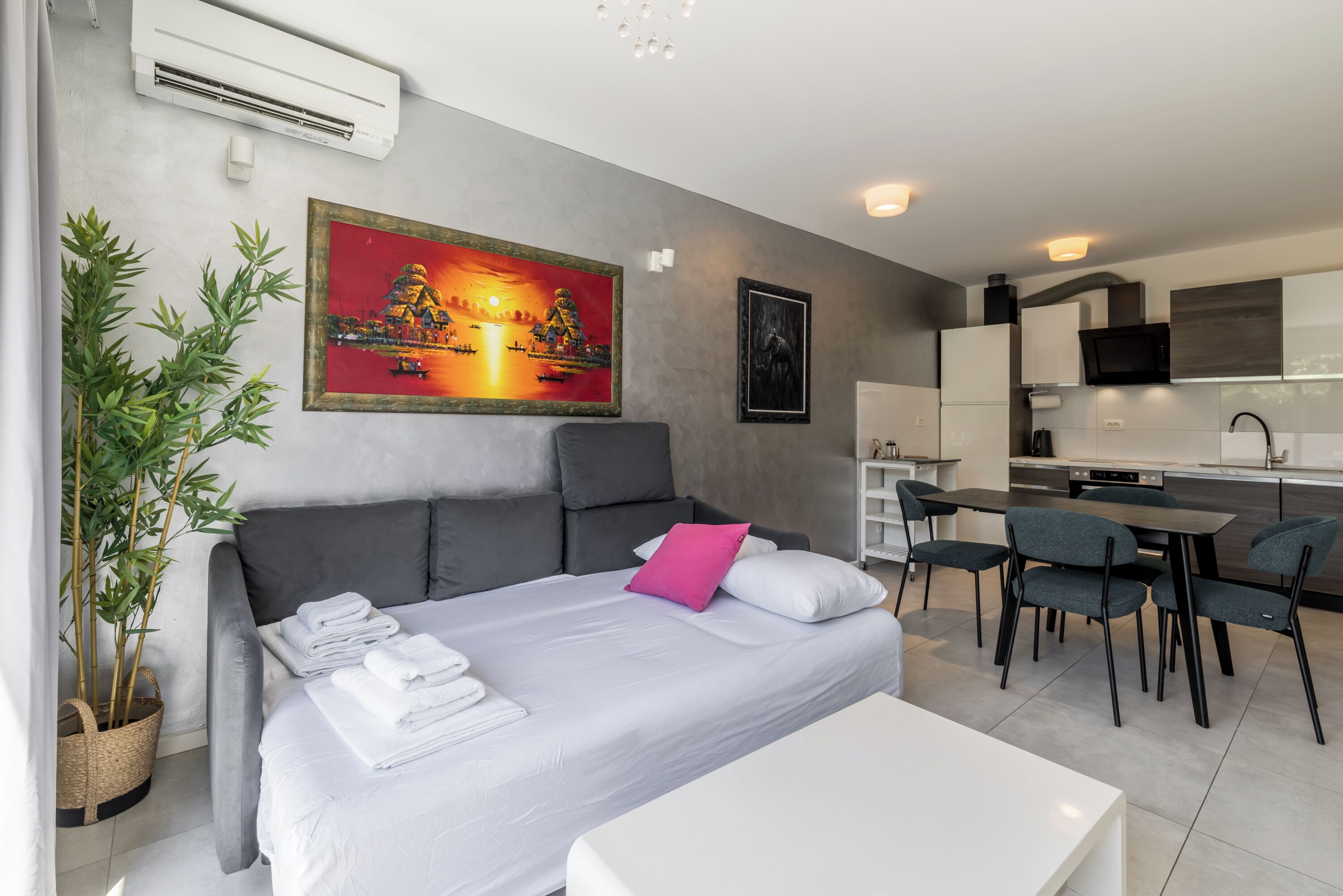 Moderni hotellihuone, jossa on sänky, ruokailutila ja keittiö.
