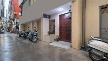 L’entrée d’un hôtel, avec une porte fermée, une enseigne et plusieurs scooters garés.