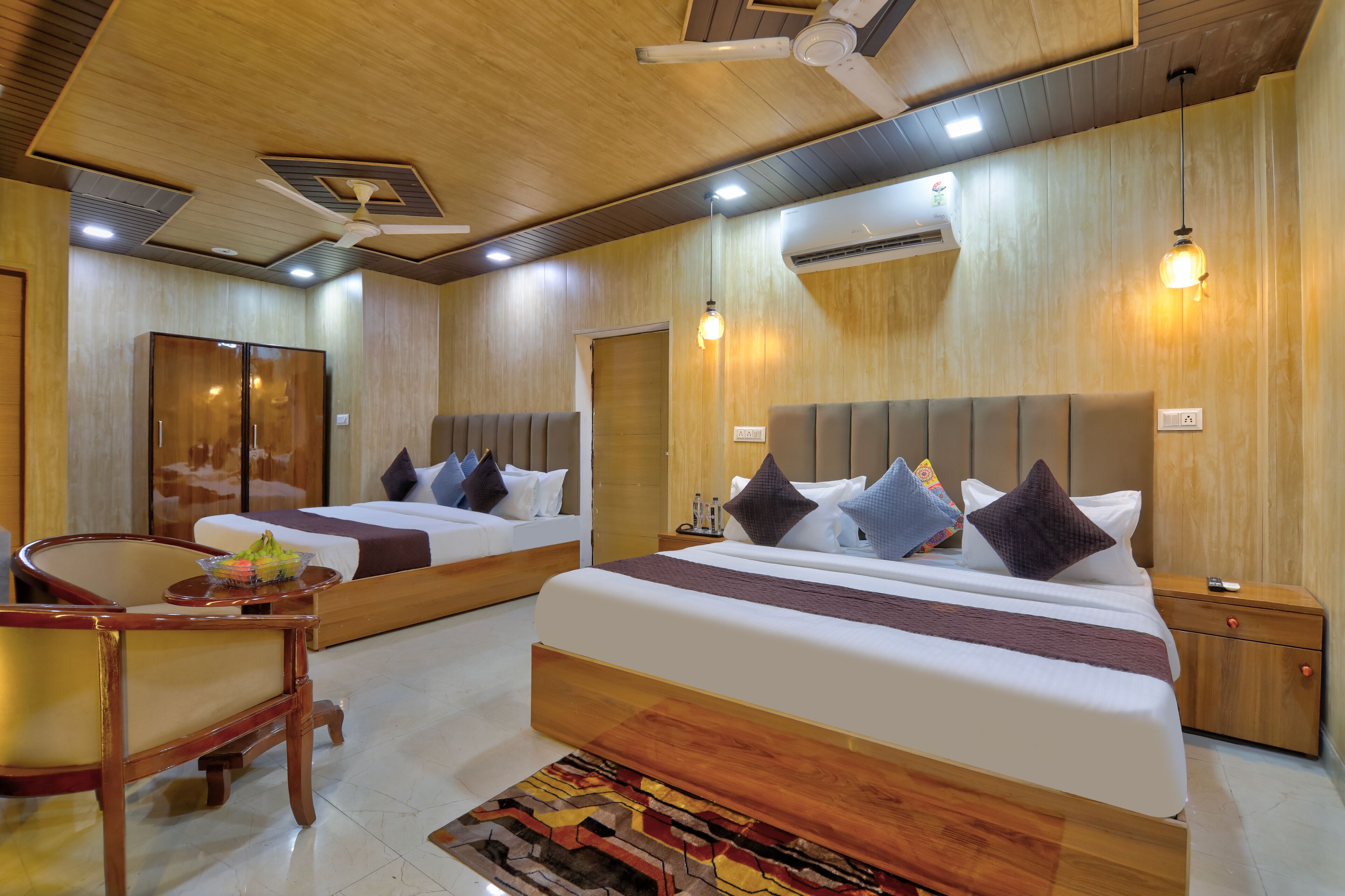 A hotel room with two beds, wooden furniture, and a ceiling fan.