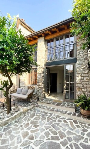 A stone patio with a built-in seating area and a tree. - Casa Limone – just steps from the lake (Castelletto)