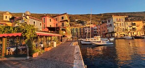 A waterfront street with buildings, a paved walkway, and boats docked along the water. - Casa Limone – just steps from the lake (Castelletto)