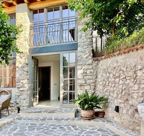 Un bâtiment en pierre doté d’un balcon, d’une porte et de plantes en pot.