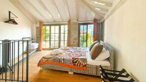 Une chambre à coucher avec un lit, une fenêtre, un balcon et une vue sur un immeuble.