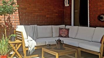 A cozy outdoor seating area with a sofa, a wooden table, and a chair.