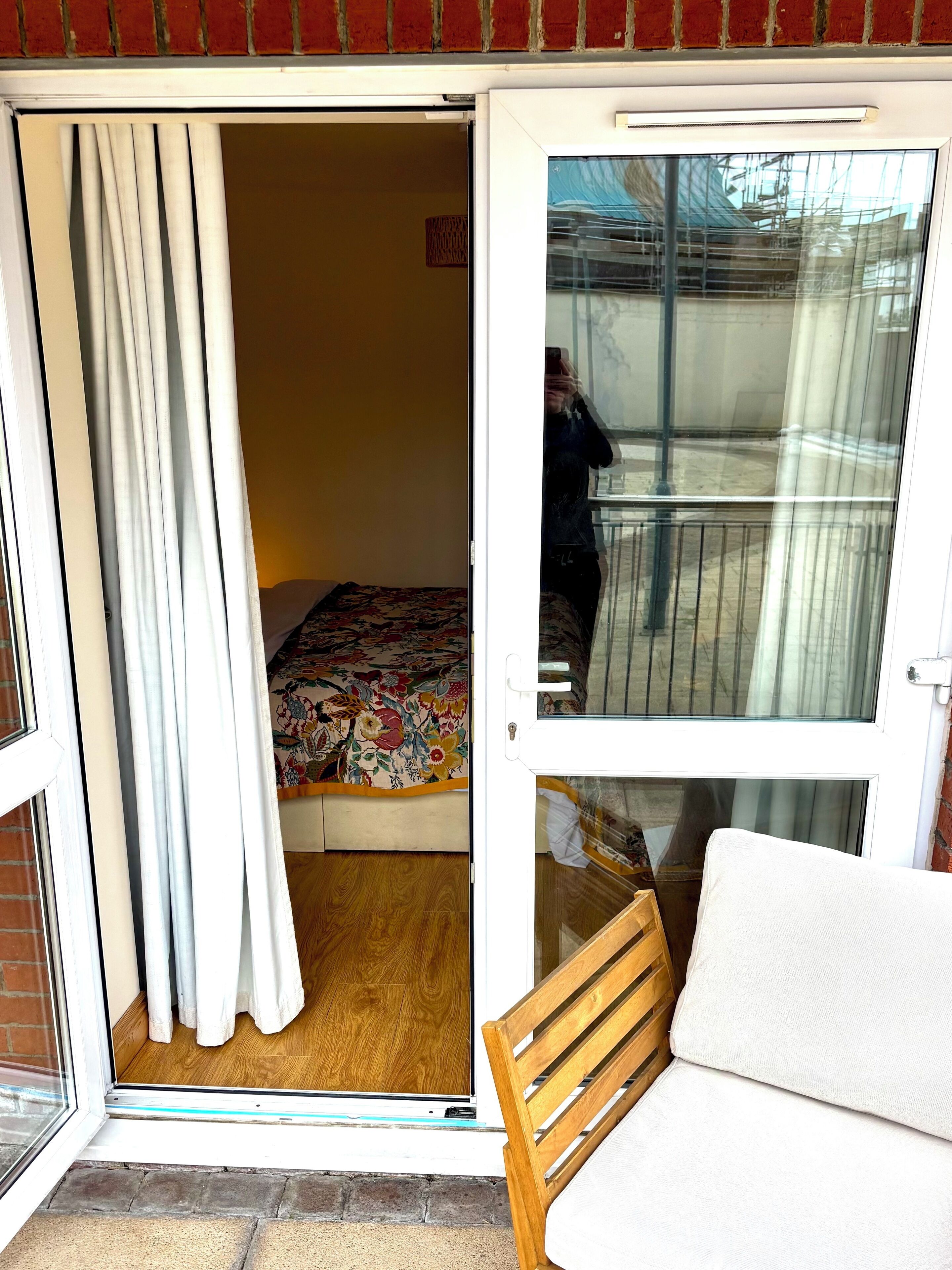 A room with a bed, a wooden bench, and a sliding glass door leading to an outdoor area.