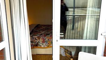 A room with a bed, a wooden bench, and a sliding glass door leading to an outdoor area.