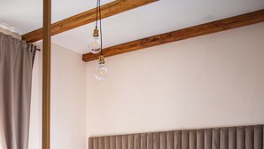 Ein Schlafzimmer mit Bett, Holzboden, Kopfteil, Nachttischen und einer Pendelleuchte.
