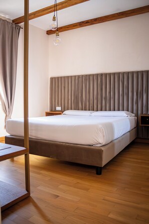 A bedroom with a bed, wooden floor, headboard, bedside tables, and a hanging light fixture. - In the heart of Rome, just a short walk from the Pantheon, renovated and featuring a terrace (Roma)
