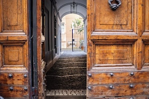 A wooden staircase leading to a courtyard with a metal gate and a bench. - In the heart of Rome, just a short walk from the Pantheon, renovated and featuring a terrace (Roma)