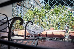 A patio area with a metal chair, potted plants, and a metal fence. - In the heart of Rome, just a short walk from the Pantheon, renovated and featuring a terrace (Roma)