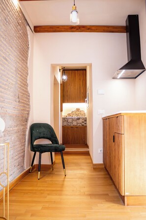 A kitchen with wooden cabinets, a black range hood, and a green chair. - In the heart of Rome, just a short walk from the Pantheon, renovated and featuring a terrace (Roma)