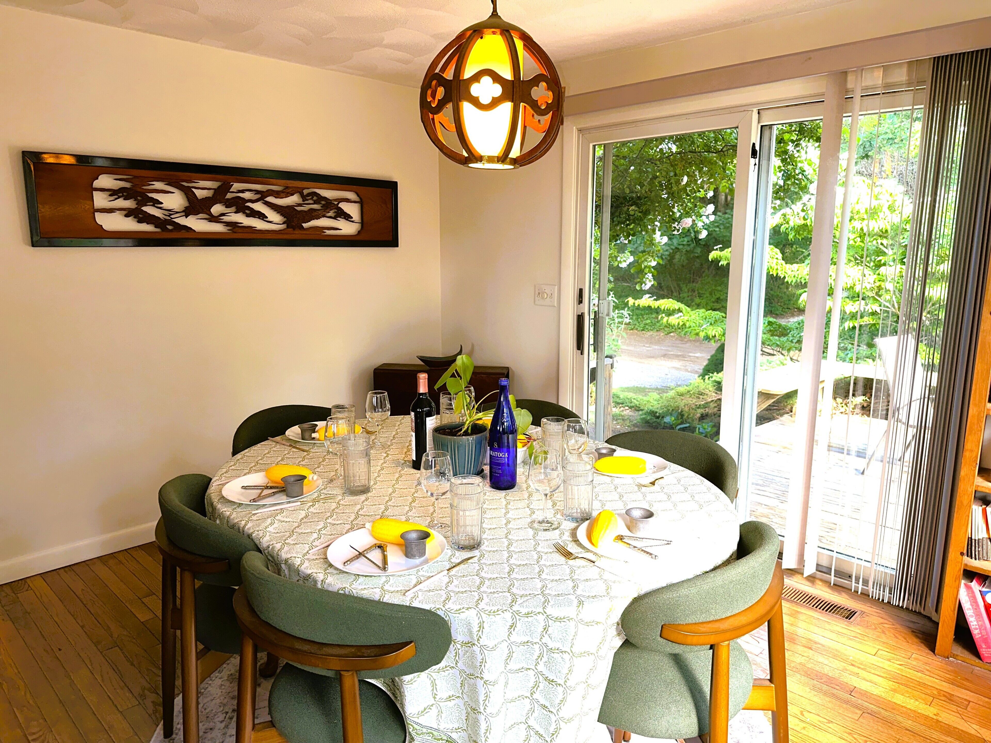 A dining table set for four with chairs, a potted plant, and a wine bottle.