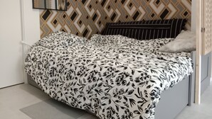 A bedroom with a patterned headboard, a bed with a floral bedspread, and a bedside table. - New apartment in a luxury residence on the waterfront of Lake Carcans. (Carcans)