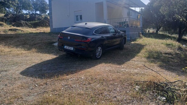 Un coche negro estacionado frente a un edificio con antena parabólica.