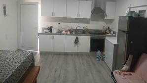 Una cocina compacta con armarios blancos, un lavamanos, una estufa y un refrigerador.