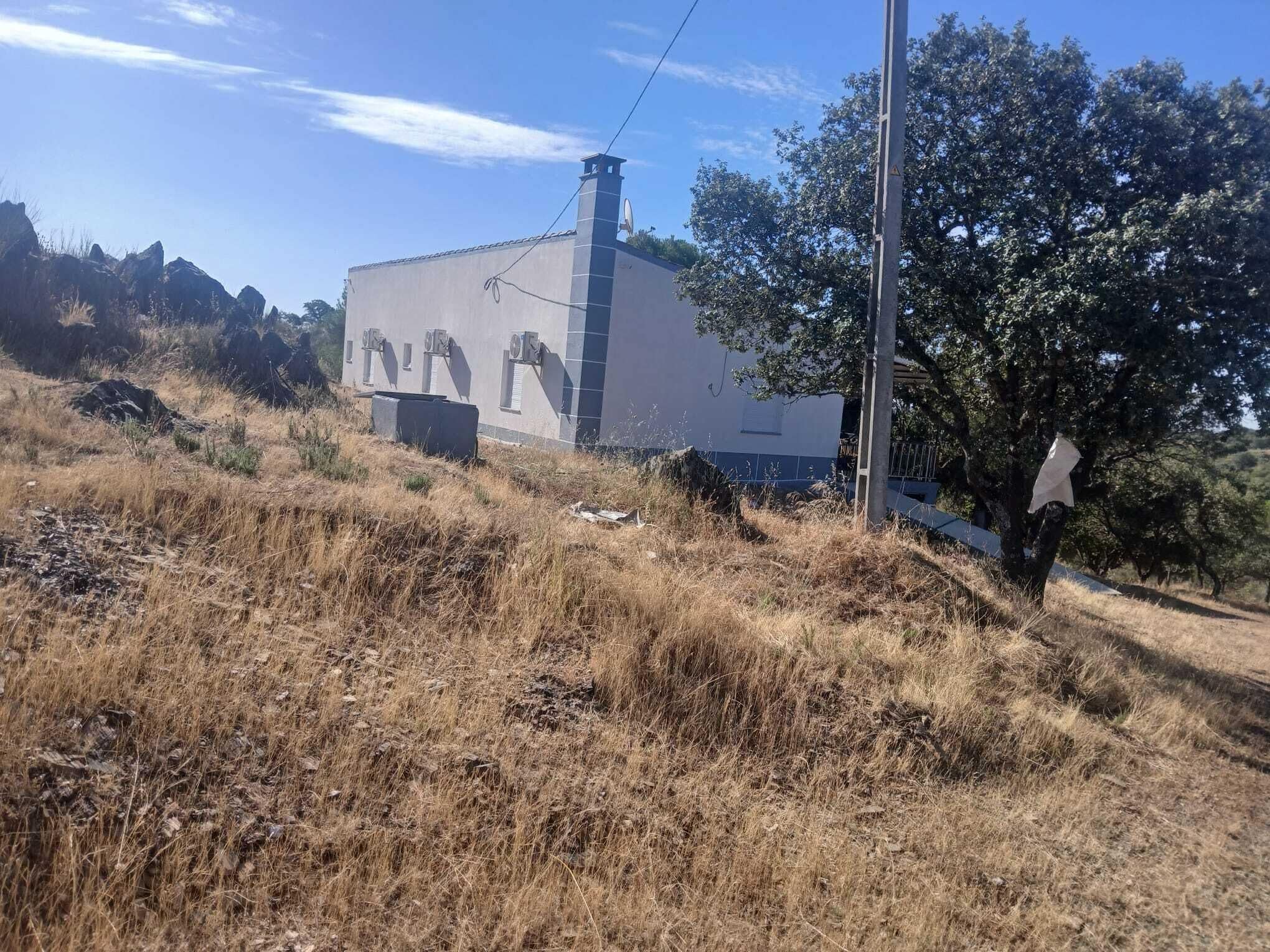 A building with a chimney, surrounded by dry grass and trees.