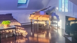 Een ruime loft met een vleugelpiano, een gezellige zithoek en een dakraam.