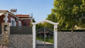 Un cancello chiuso da un muro in pietra e un cancello in metallo, con un edificio a facciata rossa e tetto a tegole.