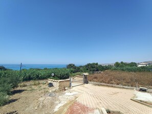 Ein gepflasterter Bereich mit einem Tor, einer Ziegelmauer und Blick aufs Meer.