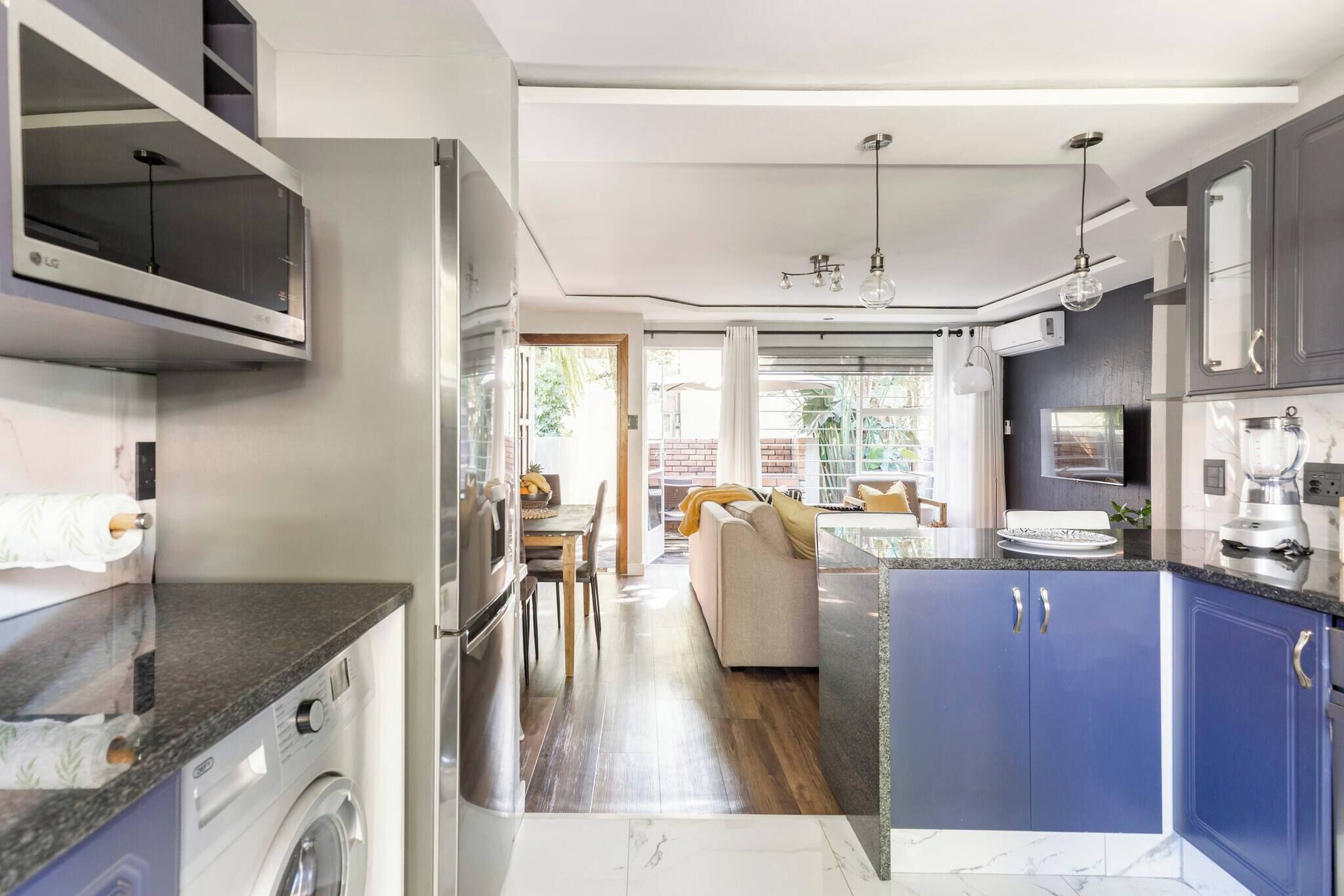 Una cocina moderna con lavadora integrada, un comedor con sofá y vistas al exterior.