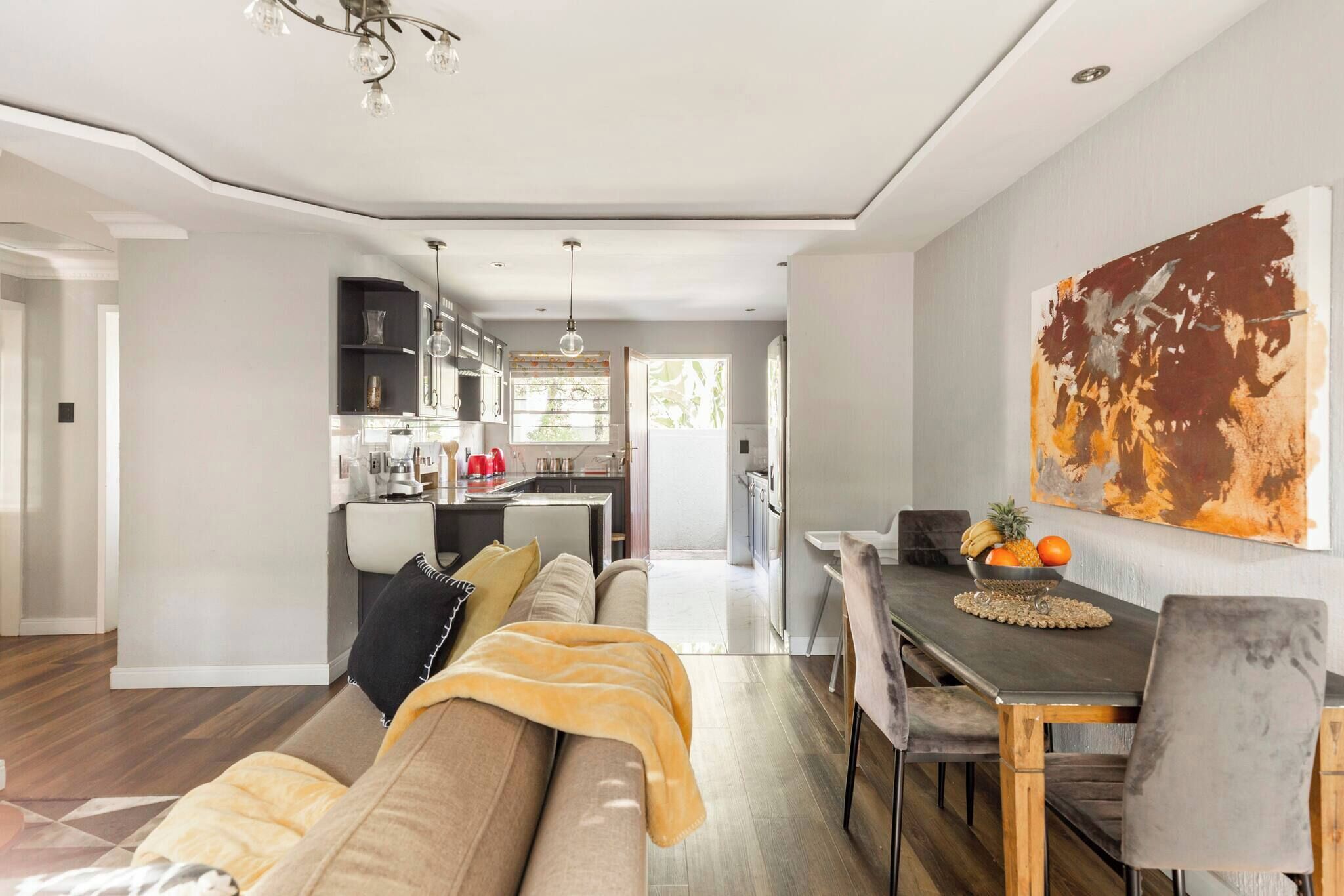 A modern living room with a sofa, dining table, and kitchen in the background.