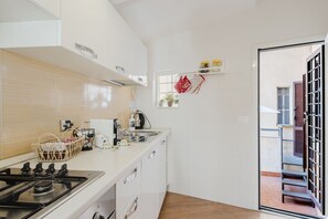 Eine moderne Küche mit weißen Schränken, einem Gasherd, einer Kaffeemaschine und einem Fenster mit Blick nach außen.