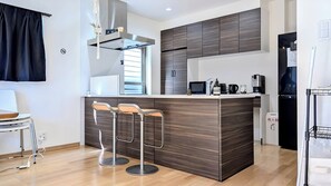 Eine moderne Küche mit einer zentralen Kochinsel, Barhocker, einer Mikrowelle und einem Kühlschrank.