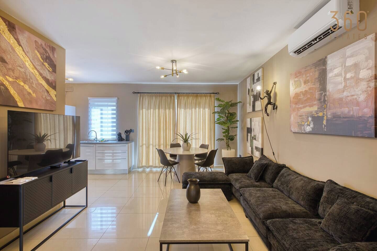 Una sala moderna con sofá, televisor, mesa de comedor y obras de arte.