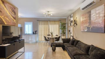 Una sala moderna con sofá, televisor, mesa de comedor y obras de arte.