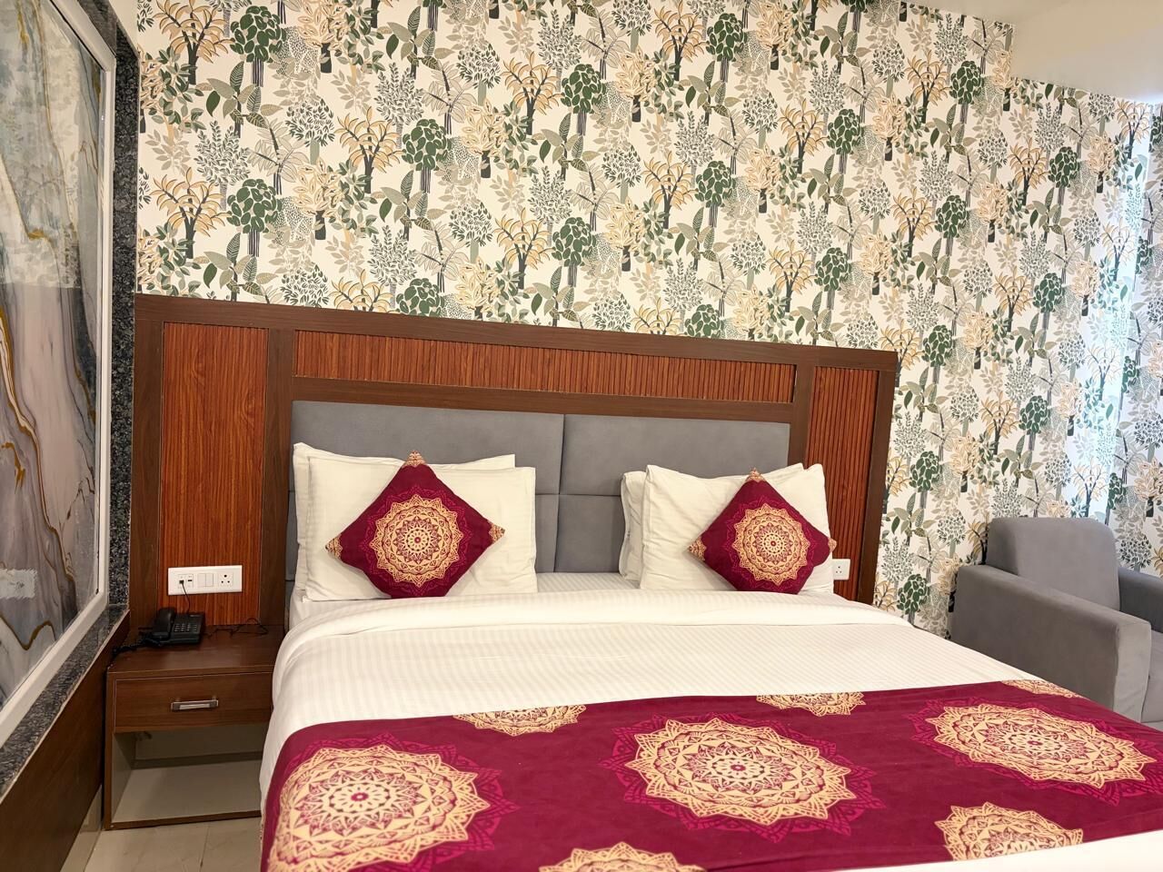 A hotel room with a bed, nightstand, and a chair.