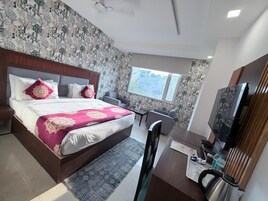 Una habitación de hotel con una cama, un escritorio, una silla, un televisor y una ventana.