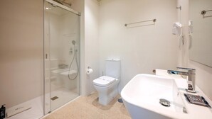 Ein modernes Badezimmer mit einer gläsernen Dusche, einer Toilette und einem Waschbecken mit Spiegel.