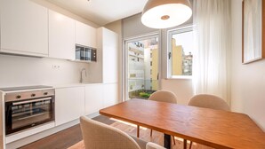 Eine moderne Küche mit weißen Schränken, einem eingebauten Backofen und einem Essbereich mit Holztisch und Stühlen.