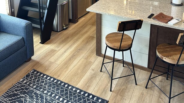 A modern kitchen with a central island, stainless steel appliances, and a wooden staircase. - Cypress Cabin - Spacious floor plan with modern look, full kitchen, separate bedroom, and upstairs loft (Bellemont)