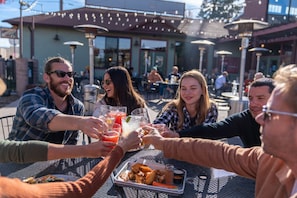Un grupo de personas brindando en una mesa de comedor al aire libre, con una bandeja de comida y bebidas.
