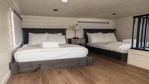 Camera da letto con due letti, pavimento in legno e comodino con lampada.