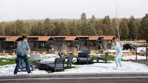 Un resort con posti a sedere all'aperto, una zona coperta e uno sfondo boschivo.