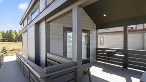 Um terraço coberto ao ar livre, com guarda-corpo, uma mesa e um banco.