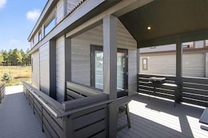 A covered outdoor deck with a railing, a table, and a bench. - Sycamore - Wheel chair accessible (Bellemont)