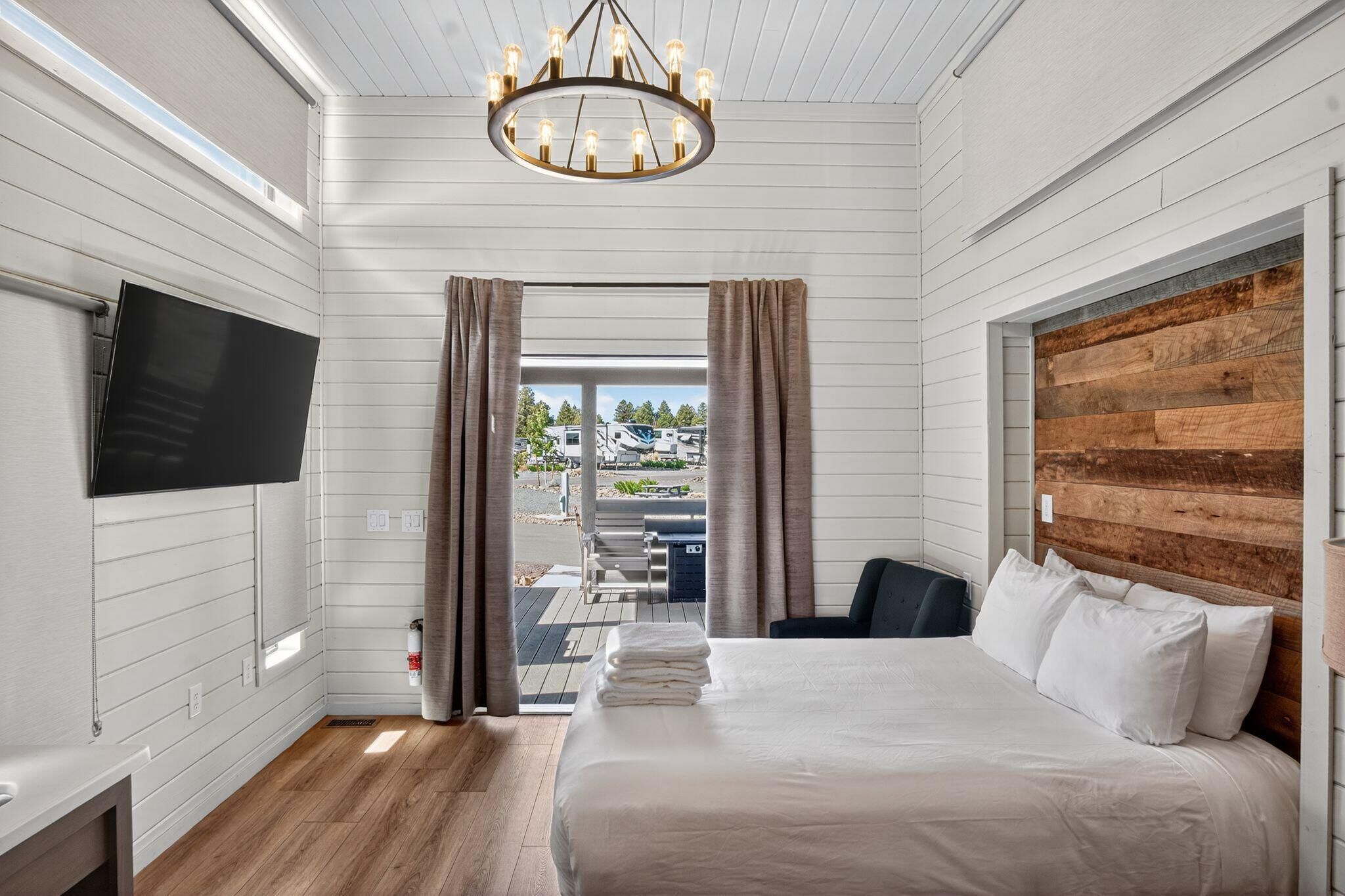 Une chambre d’hôtel avec un lit, une télévision, une tête de lit en bois et une vue sur l’extérieur.