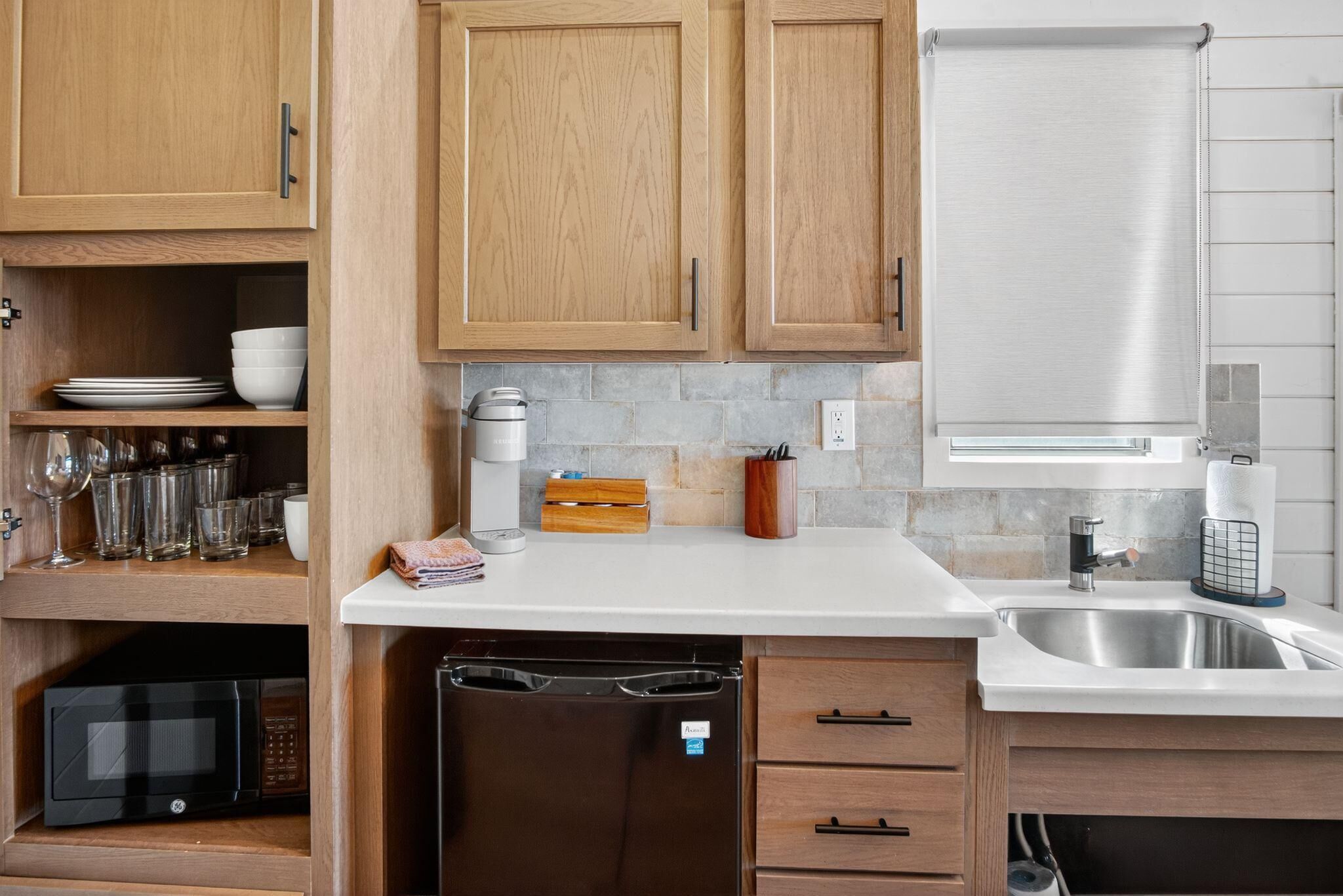 A modern kitchen with wooden cabinets, a dishwasher, a microwave, a coffee maker, and a sink.