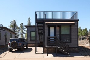 A modern two-story house with a balcony, a staircase, and a parked SUV. - Birch Cabin Roof Top Deck - Birch Cabin 3 bdrm Roof Top Deck (Bellemont)