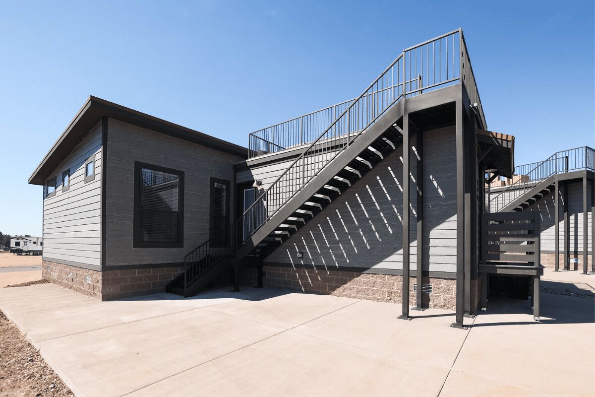 Un edificio moderno con una escalera, un pequeño porche y un cielo despejado.