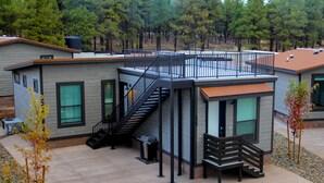 Et moderne hus med en overdækket terrasse, en trappe og et lille dækområde.