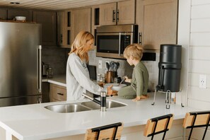 Et moderne køkken med stålemmer, en vask og træstole.