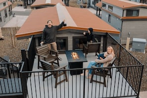 En terrasse med udendørs møbler og en bålplads, omgivet af et gelænder.