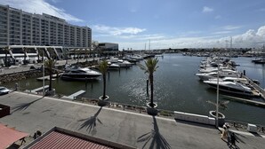A marina with boats docked, a hotel with a modern facade, and a clear sky. - Vilamoura Marina Duplex 2 by Homing (Loulé)