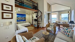A spacious living area with a high ceiling, a staircase, a dining area with a view, and a large window. - Vilamoura Marina Duplex 2 by Homing (Loulé)