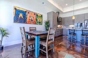 Une cuisine moderne avec un coin repas, des chaises en bois, une table et un grand tableau accroché au mur.